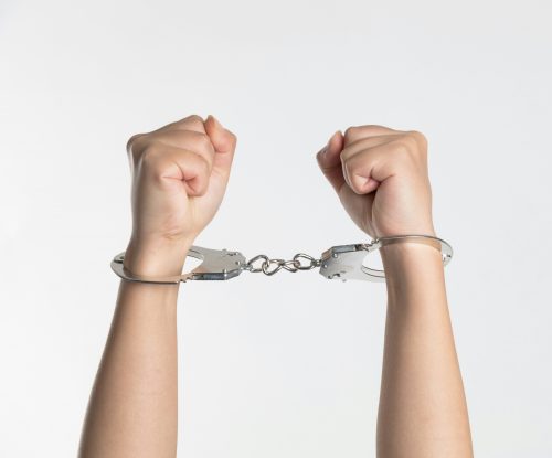 Hands held up wearing handcuffs